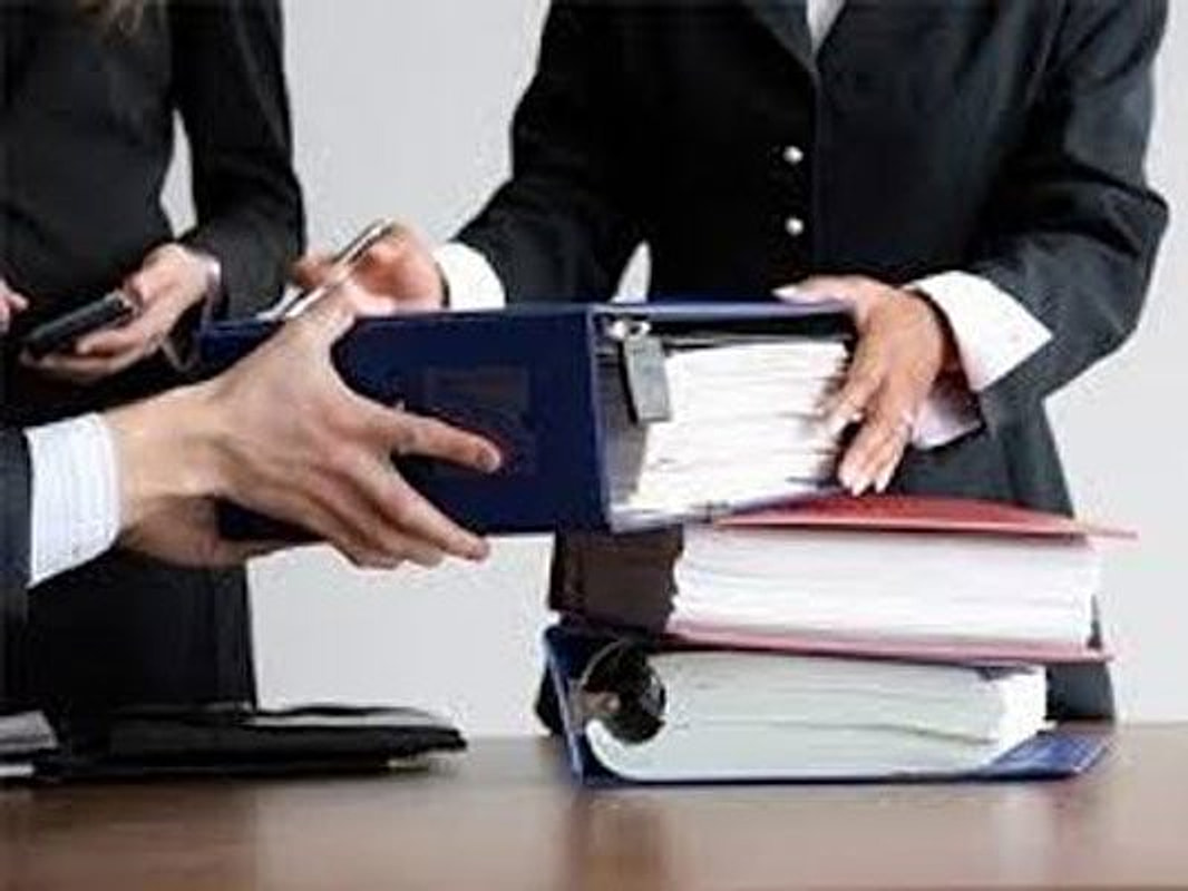 Consegna di un faldone di documenti fra professionisti